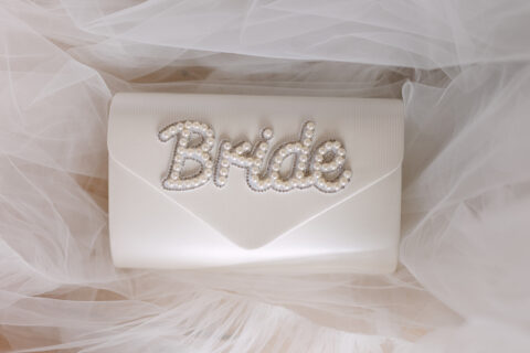 Biała torebka panny młodej z ozdobnym napisem Bride ułożona na tiulu