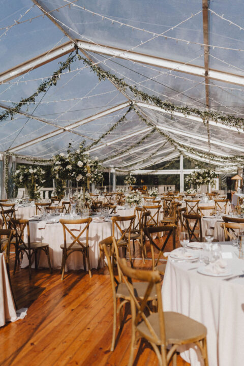 Transparentny namiot weselny udekorowany zielenią i girlandami świetlnymi